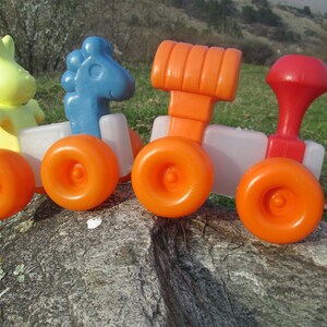 May include: A toy train with four cars, each with orange wheels. The first car has a yellow bunny on top, the second car has a blue horse, the third car has an orange block, and the fourth car has a red block.