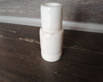 May include: A white ceramic vase with a simple, cylindrical design. The vase has a slightly textured surface and is perfect for displaying a single flower or small bouquet.