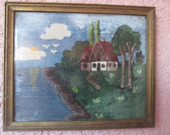 Könnte beinhalten: Ein gerahmtes Nadelbild, das ein malerisches Häuschen mit rotem Dach zeigt, eingebettet in grüne Bäume und Büsche. Das Häuschen hat weiße Fenster und einen Weg, der zu ihm führt. Der Hintergrund zeigt einen blauen Himmel mit weißen Wolken und ein Gewässer.