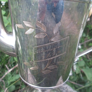 May include: A silver teapot with an engraved floral design and the inscription "Wedding Present 4. 1. 93".