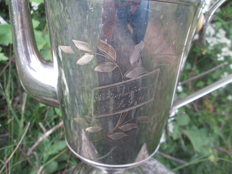 May include: A silver teapot with an engraved floral design and the inscription "Wedding Present 4. 1. 93".