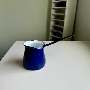 May include: A small blue enamel coffee pot with a white interior and a black handle.