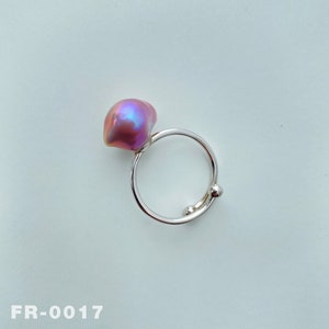 May include: A silver ring with a pink iridescent pearl. The ring has a simple design with a round pearl set on a thin band.