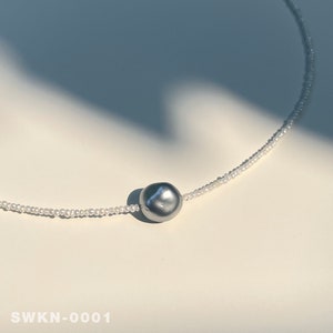 May include: A silver pearl necklace with a single large gray pearl pendant.