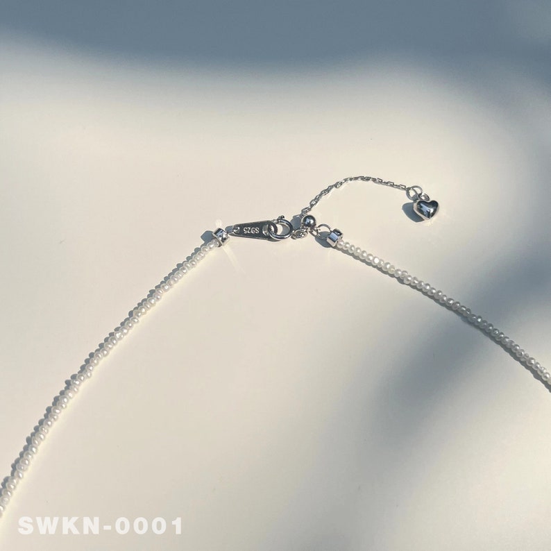 May include: A delicate silver necklace with a small heart charm and a beaded chain. The necklace is adjustable with an extender chain.