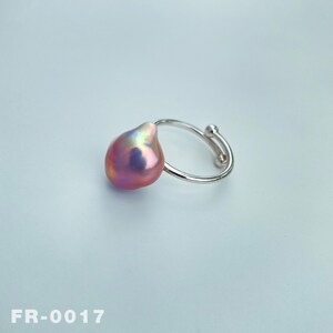 May include: A silver ring with a large, pink baroque pearl. The pearl has an iridescent sheen.