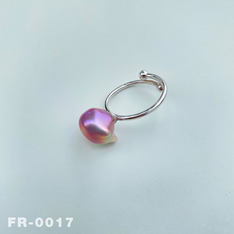 May include: A silver ring with a pink baroque pearl. The ring is open and has a curved band.