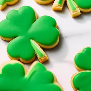 Può includere: Biscotti di zucchero verdi decorati con glassa verde a forma di trifogli a quattro foglie.