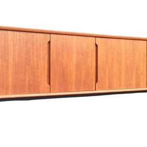 May include: A mid-century modern teak sideboard with three doors and two drawers. The sideboard has black metal legs and a light wood finish.