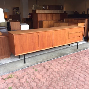 May include: A mid-century modern teak sideboard with four doors and three drawers. The sideboard has black metal legs and is in good condition.