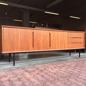 May include: A mid-century modern teak sideboard with four doors and two drawers. The sideboard has black metal legs and is in good condition.