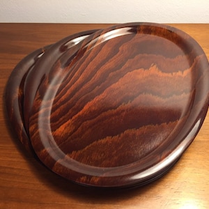 Puede incluir: Juego de cuatro bandejas ovaladas de madera con acabado de grano de madera marrón oscuro.