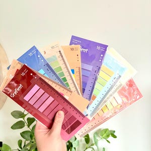May include: A hand holding a fan of colorful sticky note sets. Each set includes a ruler and a gradient of 10 color sticky notes. The text "Gradient" is visible on one of the sets.
