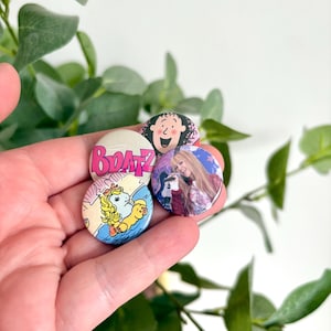 Peut inclure: Quatre boutons ronds avec des graphiques colorés sont tenus dans une main. Les boutons présentent des images de personnages de dessins animés et le mot "Bratz". Un bouton représente un poney de dessin animé. Les boutons mesurent environ 2,5 cm de diamètre.