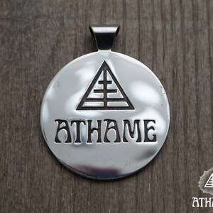 May include: Silver pendant with a triangle and the word "ATHAME" engraved on it.