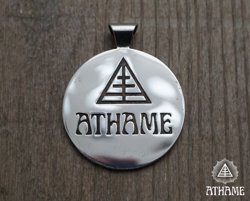May include: Silver pendant with a triangle and the word "ATHAME" engraved on it.