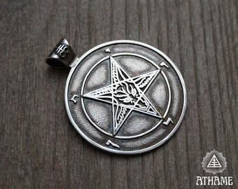 May include: Silver pendant featuring a pentagram with a goat's head inside, surrounded by a circle of symbols. The pendant is on a wooden surface.