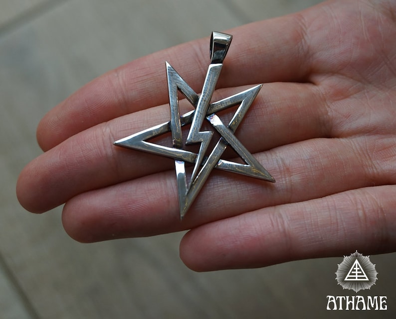 May include: A silver pendant in the shape of a five-pointed star with a complex, interwoven design. The star is a pentagram, a symbol with a long history of use in various cultures and religions.