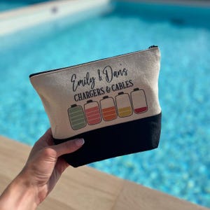 May include: A beige canvas zippered pouch with black trim. The pouch has the text "Emily & Davis CHARGERS & CABLES" printed on it. Five colorful battery icons are printed below the text.