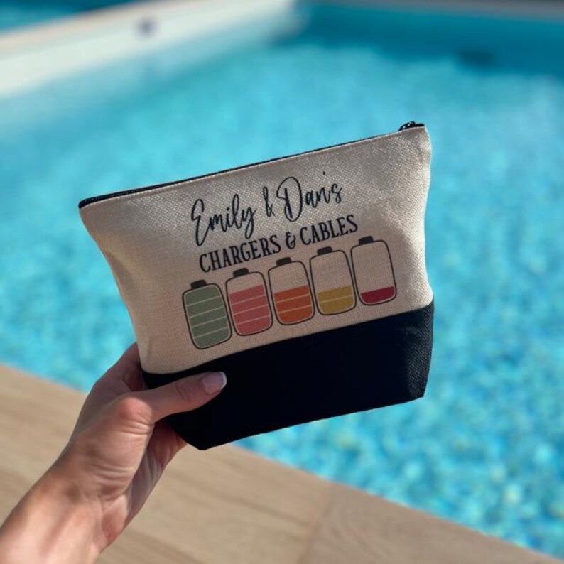 May include: A beige canvas zippered pouch with black trim. The pouch has the text "Emily & Davis CHARGERS & CABLES" printed on it. Five colorful battery icons are printed below the text.