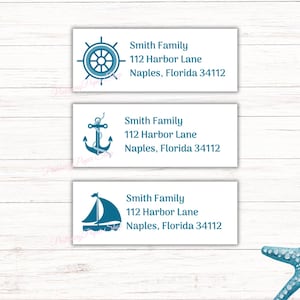 Puede incluir: Tres etiquetas blancas con diseños náuticos azules y texto. La etiqueta superior tiene un timón de barco, la etiqueta del medio tiene un ancla y la etiqueta inferior tiene un velero. Cada etiqueta tiene el texto "Smith Family", "112 Harbor Lane", "Naples, Florida 34112".