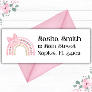 Op de afbeelding: Een wit adreslabel met een roze en witte regenboog met een strik erop. De tekst op het label luidt "Sasha Smith, 12 Main Street, Naples, FL 34102".
