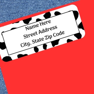 May include: Black and white cow print address label with the text "Name Here", "Street Address", and "City, State Zip Code".