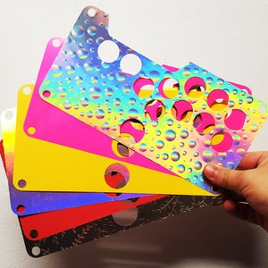 May include: A set of five colorful, iridescent, and translucent plastic sheets with a pattern of circles. The sheets are layered on top of each other, creating a rainbow effect.