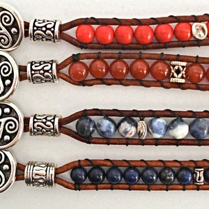 Könnte beinhalten: Vier Lederarmbänder mit verschiedenen farbigen Edelsteinperlen. Jedes Armband hat einen silbernen Verschluss mit einem keltischen Knotendesign.