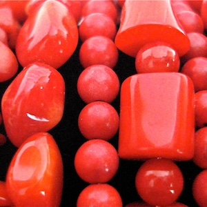 Puede incluir: Un collar de coral rojo de cerca. El collar está hecho de cuentas de coral de varias formas y tamaños, incluyendo cuentas redondas, ovaladas y rectangulares.