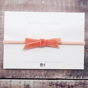May include: A peach-colored velvet bow headband on a white card with the text "briege+rose" and website information.