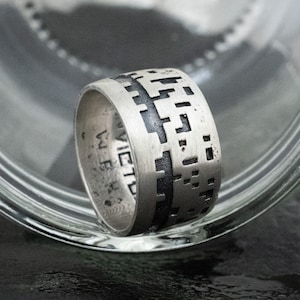 May include: A silver ring with a black geometric pattern and the word "VICTORY" engraved on the side.