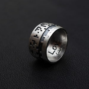 May include: A silver ring featuring a geometric pattern and the word "Love" engraved on the side.