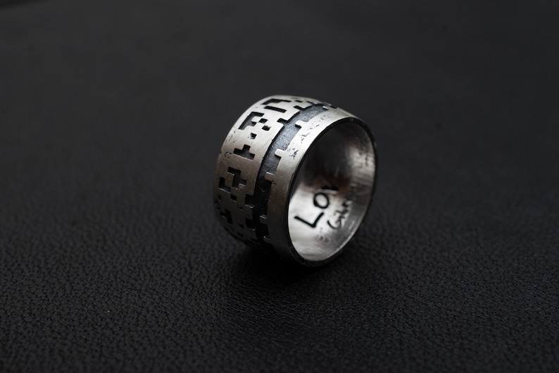 May include: A silver ring featuring a geometric pattern and the word "Love" engraved on the side.