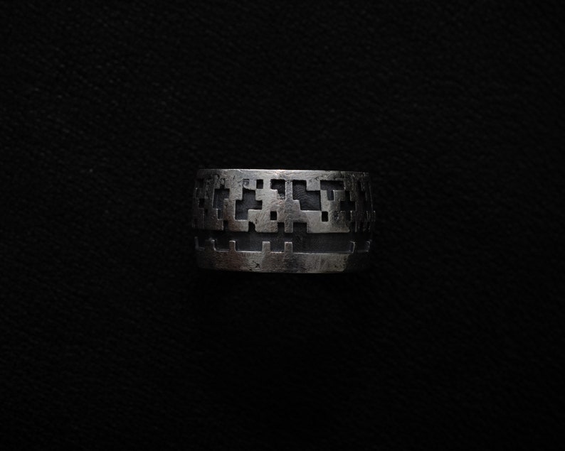 May include: A silver ring with a geometric pattern design.