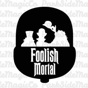 May include: Black and white graphic featuring silhouettes of characters inside a stylized shape. The text "Foolish Mortal" is displayed in a gothic font below the silhouettes. The design is likely inspired by a theme park attraction.