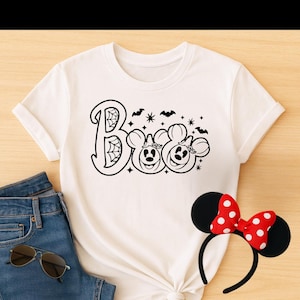 May include: White t-shirt featuring a black graphic of Mickey Mouse and Minnie Mouse dressed as pumpkins with the text "Boo" above them. The graphic includes bats, stars, and a spider web.