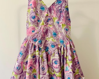 May include: A sleeveless, purple, pink, and blue floral print dress with a fitted bodice and a full skirt. The dress has a V-neckline and is made of a silky fabric.