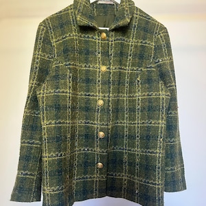 Può includere: Una giacca a maniche lunghe con un motivo a quadri testurizzato in verde oliva e blu navy scuro. La giacca presenta un colletto strutturato, cinque bottoni rotondi in metallo dorato sul davanti e un'etichetta all'interno del colletto con la scritta la femme.