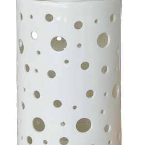 May include: White ceramic oil diffuser with a circular design of holes. The diffuser is cylindrical and has a smooth, white finish.