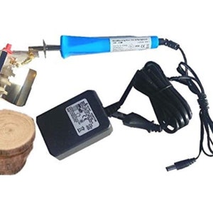 Pode incluir: Uma ferramenta de queima de madeira azul com um adaptador de energia preto e um cabo. A ferramenta tem um acessório de metal com uma maçaneta vermelha. Também há rodadas de madeira na imagem.