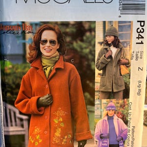 May include: McCall's sewing pattern featuring a woman's coat with floral embroidery. The pattern includes views A, B, and C, with size Z (Lrg-Xlg). The cover shows a woman wearing the coat in orange, with the text "Woman's Day Collection".