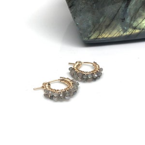 Peut inclure: Une paire de boucles d'oreilles créoles en or avec des pierres précieuses de labradorite. Les boucles d'oreilles sont petites et délicates, et seraient un excellent cadeau pour une personne spéciale.