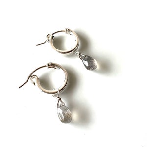 Peut inclure: Une paire de boucles d'oreilles créoles en argent avec une pierre précieuse grise en forme de larme suspendue à chaque créole.