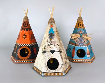 May include: Three decorative teepees made of paper with different designs. The teepees are decorated with feathers, beads, and other Native American inspired designs. The teepees are all the same size and are arranged in a row. The teepee in the middle has the words "love my tribe" written on it.