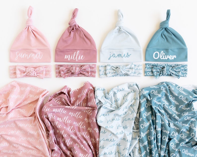 May include: Four sets of baby accessories in pink, rose, light blue, and teal. Each set includes a knotted hat, a headband, and a swaddle blanket. The hats, headbands, and blankets are all personalized with the names "Summer", "Millie", "James", and "Oliver" in white script.