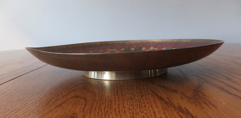 May include: A brown oval-shaped serving dish with a decorative pattern in shades of red, blue, and green. The dish has a silver-coloured base.
