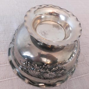 K&ouml;nnte beinhalten: Silberne Sch&uuml;ssel mit gewelltem Rand und Blumenmuster. Die Sch&uuml;ssel ist aus Metall und hat eine gl&auml;nzende Oberfl&auml;che.