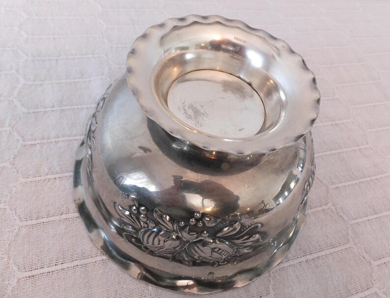 K&ouml;nnte beinhalten: Silberne Sch&uuml;ssel mit gewelltem Rand und Blumenmuster. Die Sch&uuml;ssel ist aus Metall und hat eine gl&auml;nzende Oberfl&auml;che.