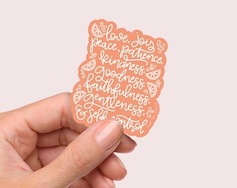 May include: A peach-colored sticker with white lettering and lemon slice illustrations. The text reads "love, joy, peace, patience, kindness, goodness, faithfulness, gentleness, & self control."